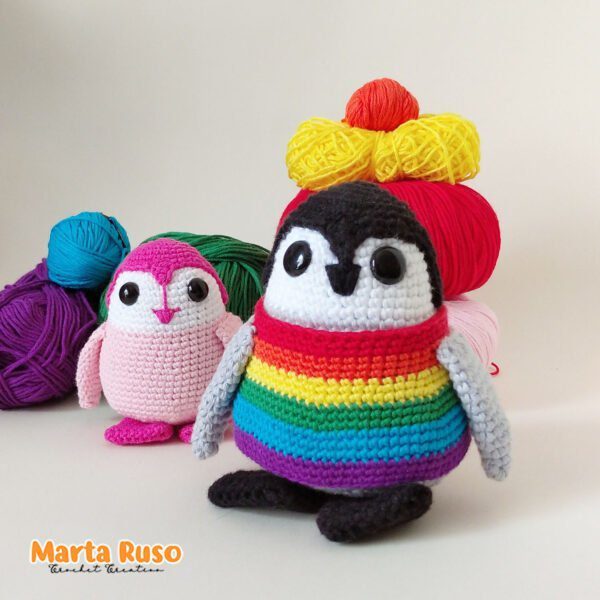 Laponio el pingüino amigurumi, que he vestido con un chaleco con los colores del Orgullo, junto con la versión rosa y más pequeña del pingüino.